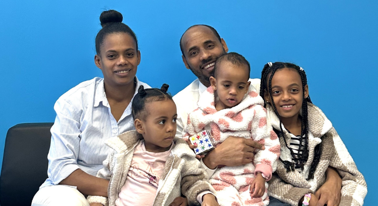 Habtom and Mihret with big smiles sit with their three daughters on their laps. 