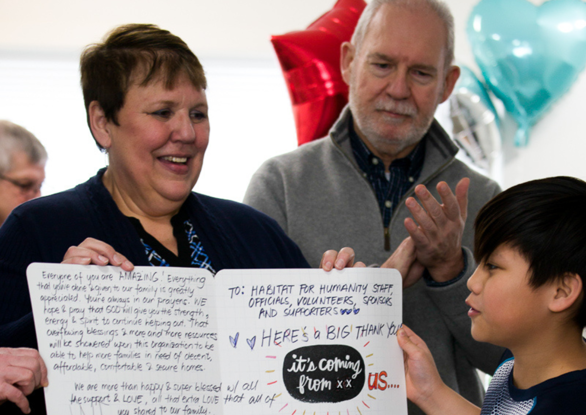 Volunteer Marilyn accepts a handwritten thank you card from child of Habitat for Humanity homeowner