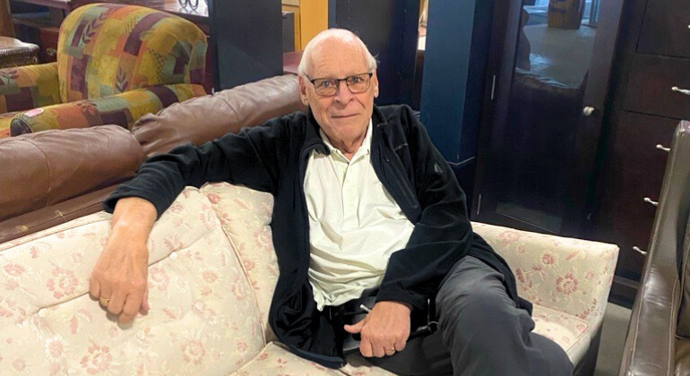 Doug sits on a sofa at Habitat ReStore Sunridge Way where he is meeting the newest volunteers for onboarding.