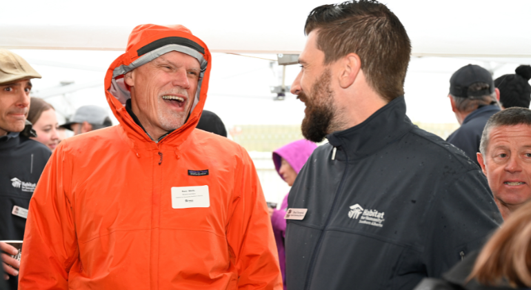 Russ shares a laugh with a Habitat staffer at a groundbreaking event in Airdrie.