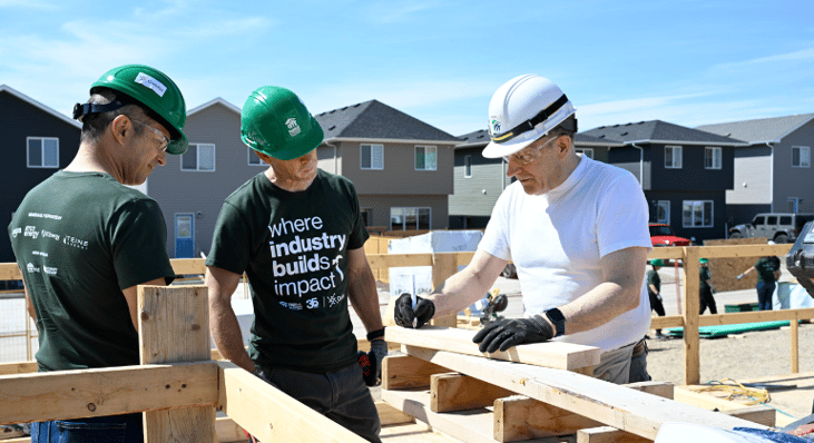 Two volunteers from Ovintiv learning how to build an exterior wall with Habitat Crew Leader Brian.  