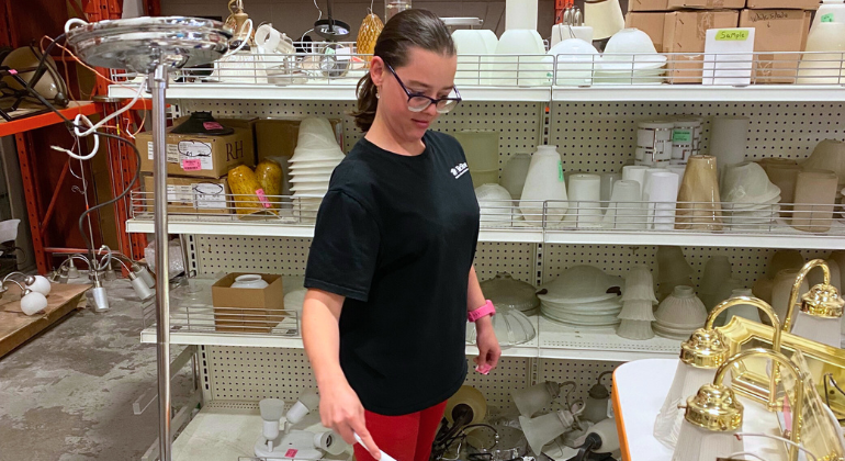 Susan dusting light fixtures at Habitat ReStore.