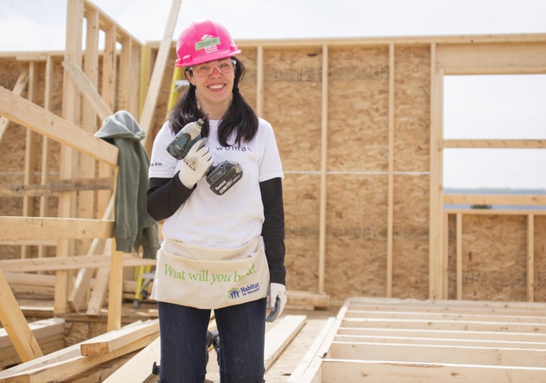 A volunteer holds a drill on a Habitat construction site.