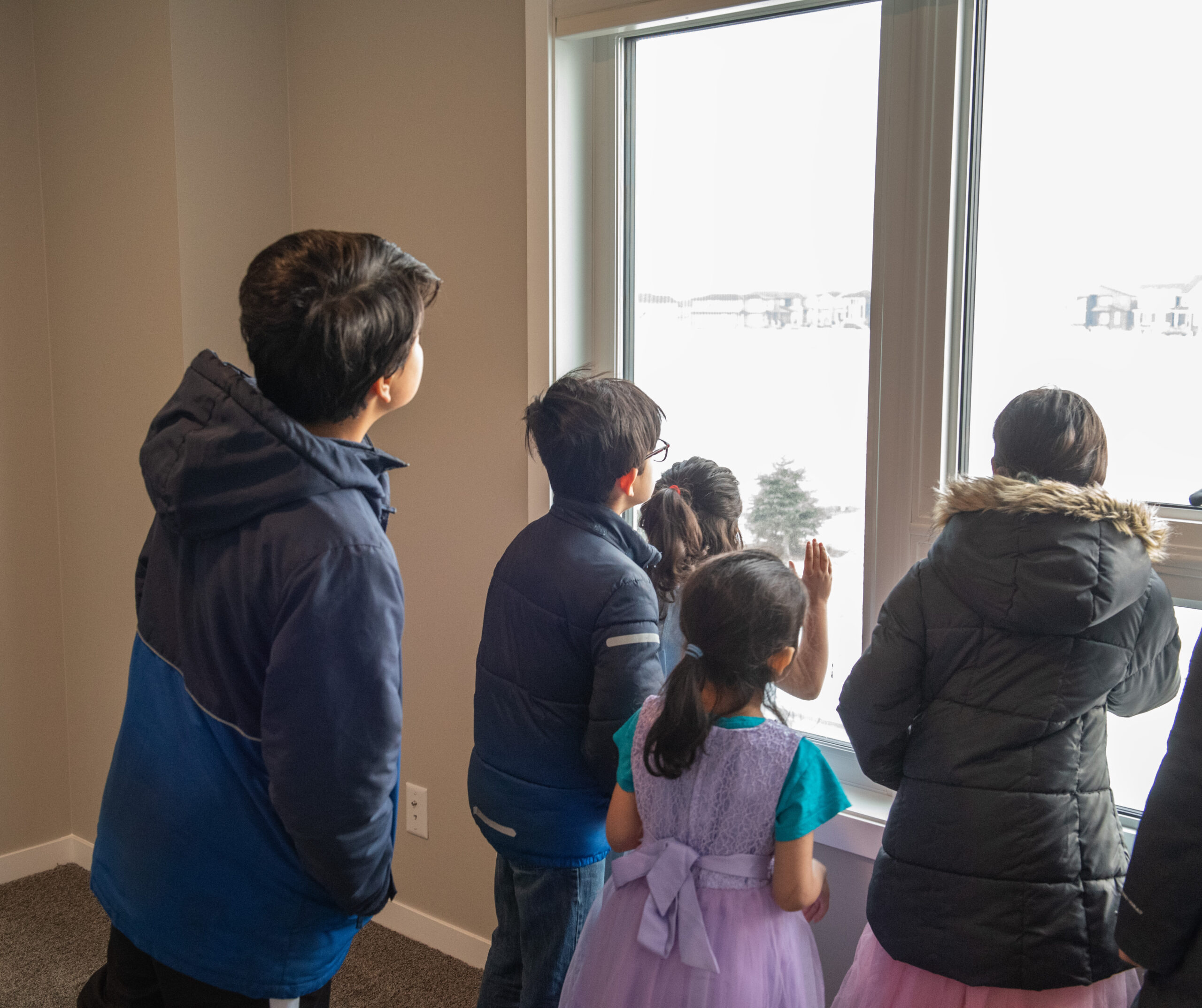 Five children looking out a window at their new backyard