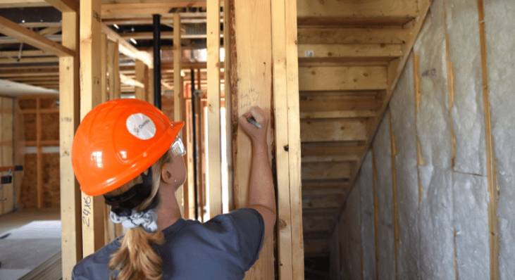 A woman writing a message on a stud in a home under construction.