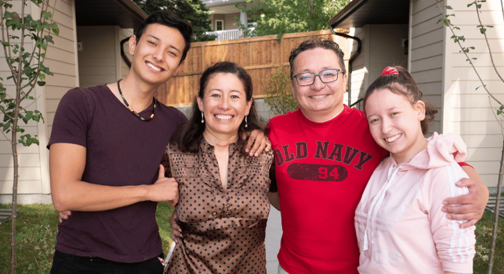 A smiling family outside of their Habitat home
