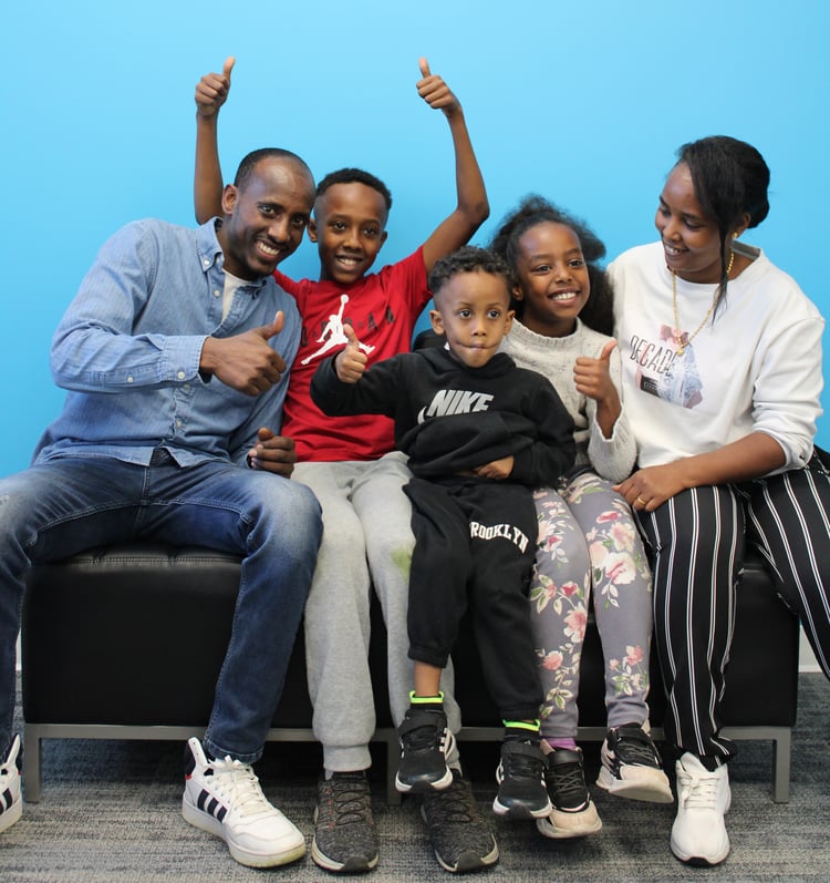 A smiling family giving thumbs-up to the camera.