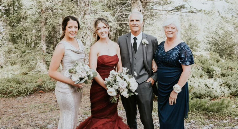 A man in between 3 women all wearing formal wear in a forest