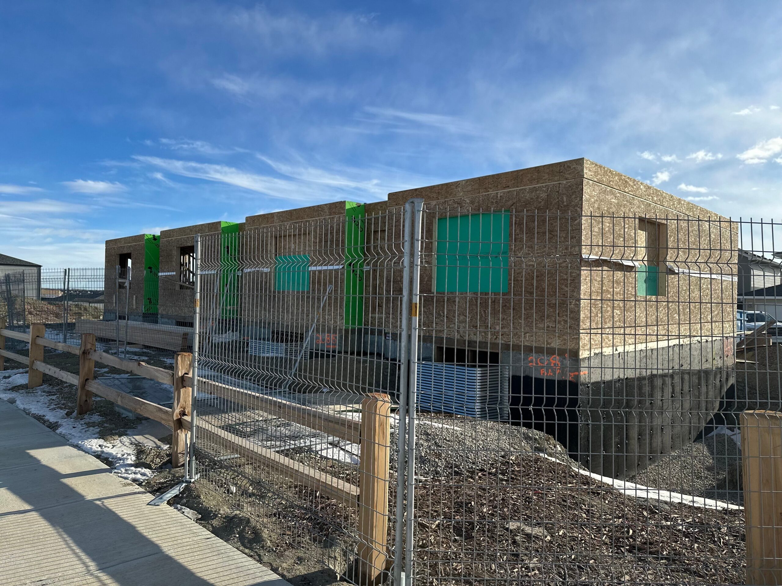 A townhome under construction behind a metal fence