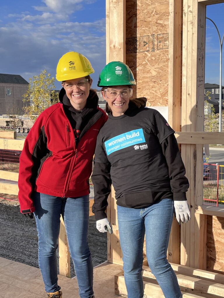 Two women wearing hardhats on a construction site