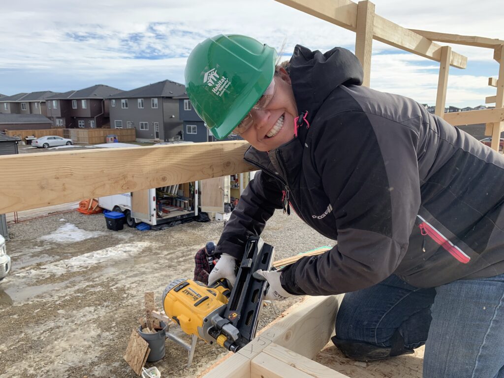 Habitat volunteer holding a nail gun on a construction site