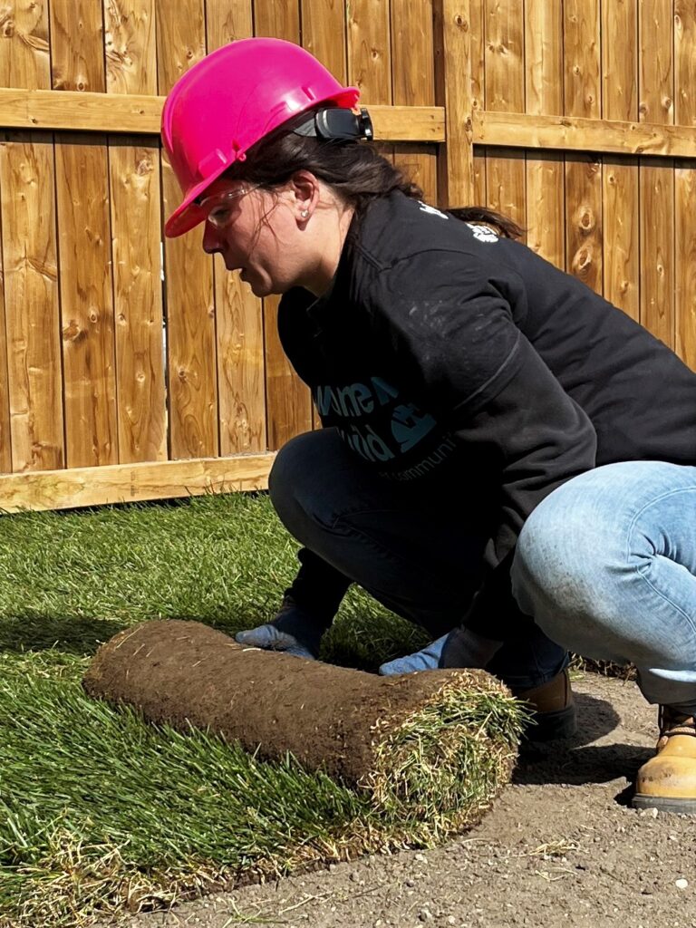 Women wearing pink hardhat rolling out new grass