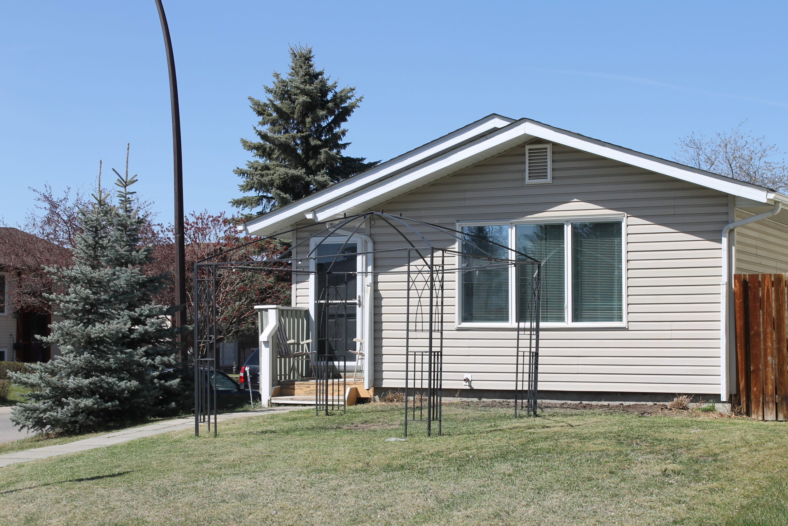 Exterior of a single family home in Calgary with green grass, mature trees on a corner lot.