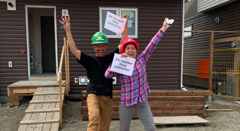 Habitat homeowners hold signs that say 500 volunteers hours completed.
