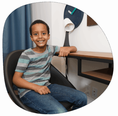 Young boy sitting at a desk of his new Habitat for Humanity home smiling at the camera.
