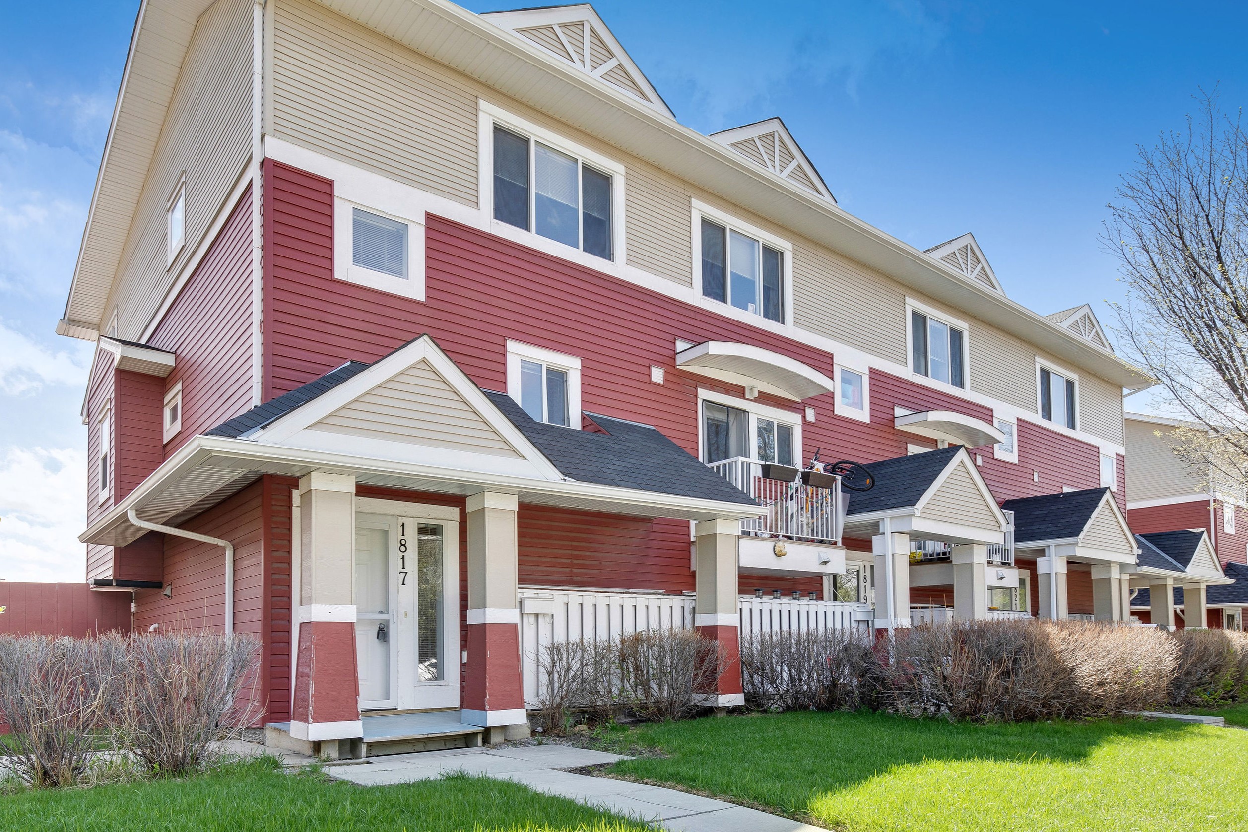 Exterior of row townhomes with red and tan siding.