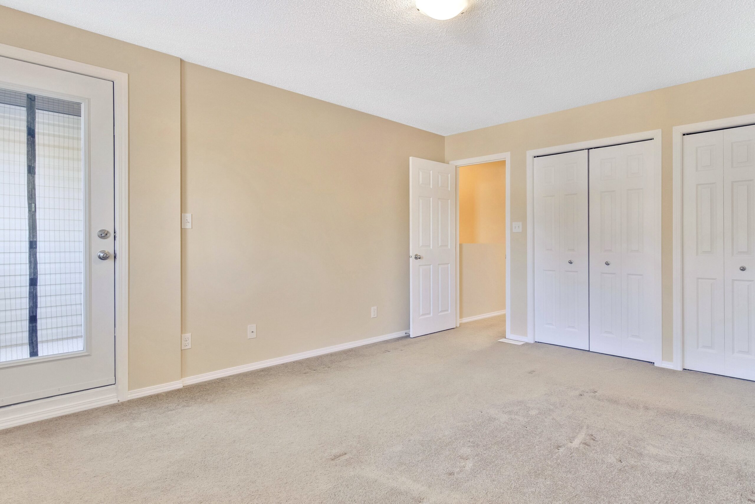 Master suite of a Habitat home showing two closets and an entrance to a private patio.
