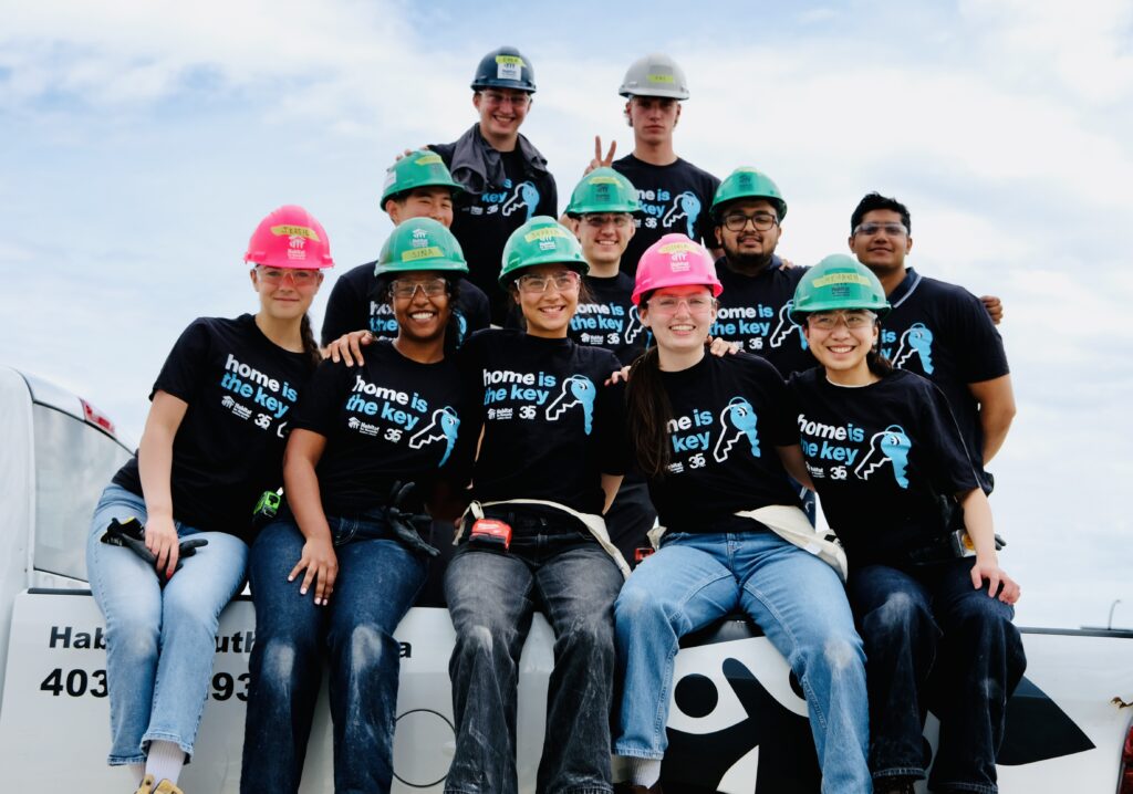 A group of people on a construction site wearing hardhats sitting on a Habitat truck