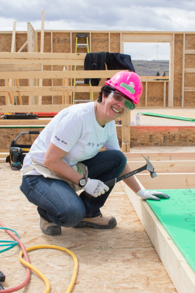 Women holding hammer wearing a pink hardhat