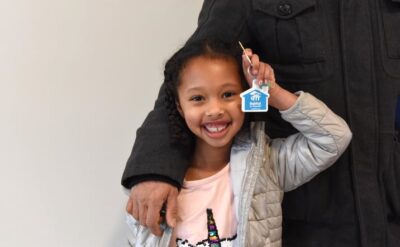 A little girl smiles proudly holding a Habitat housekey.