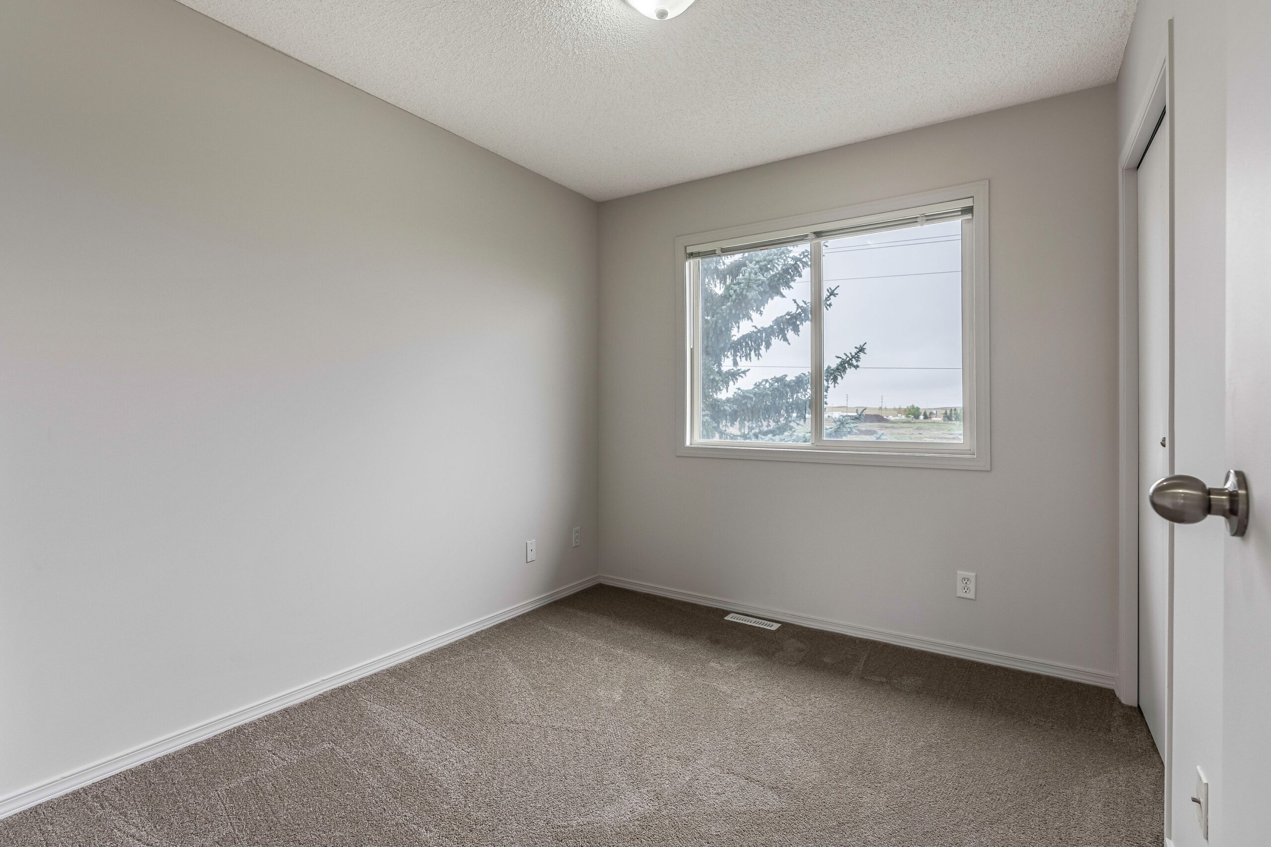 Vacant, well-lit bedroom in a Habitat home in Calgary.