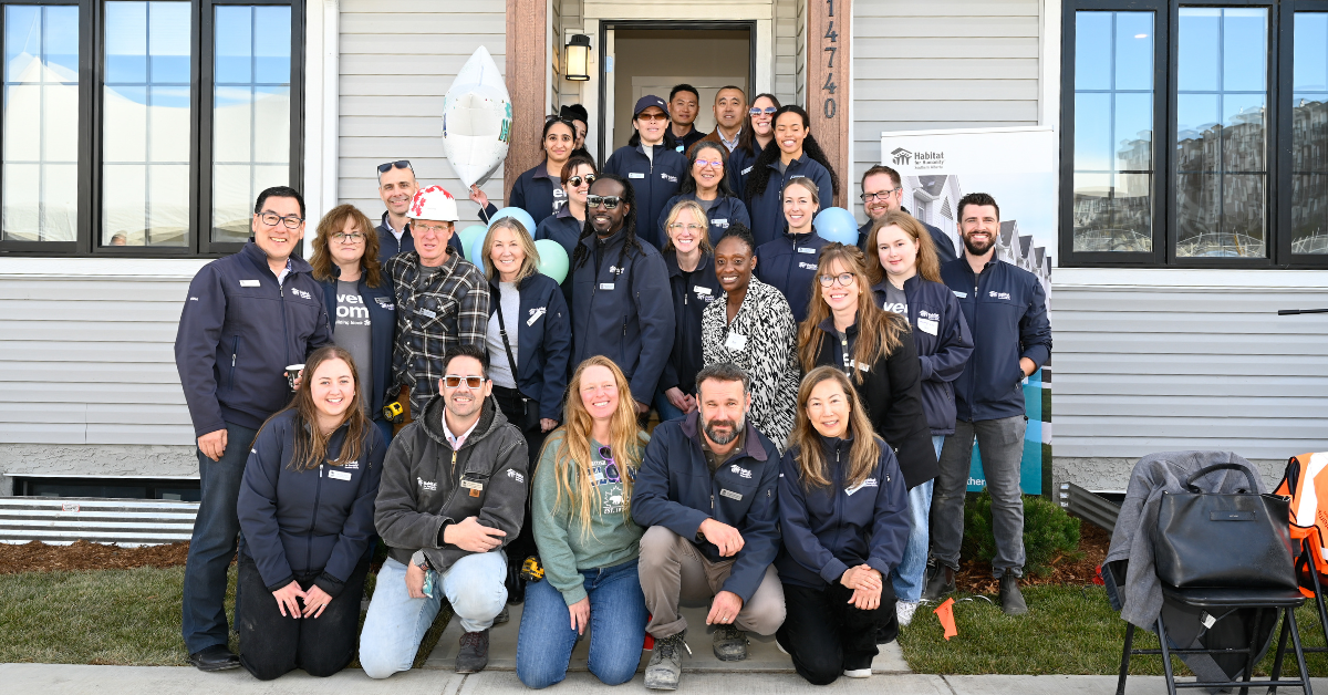 Habitat staff photo in front of a finished townhome