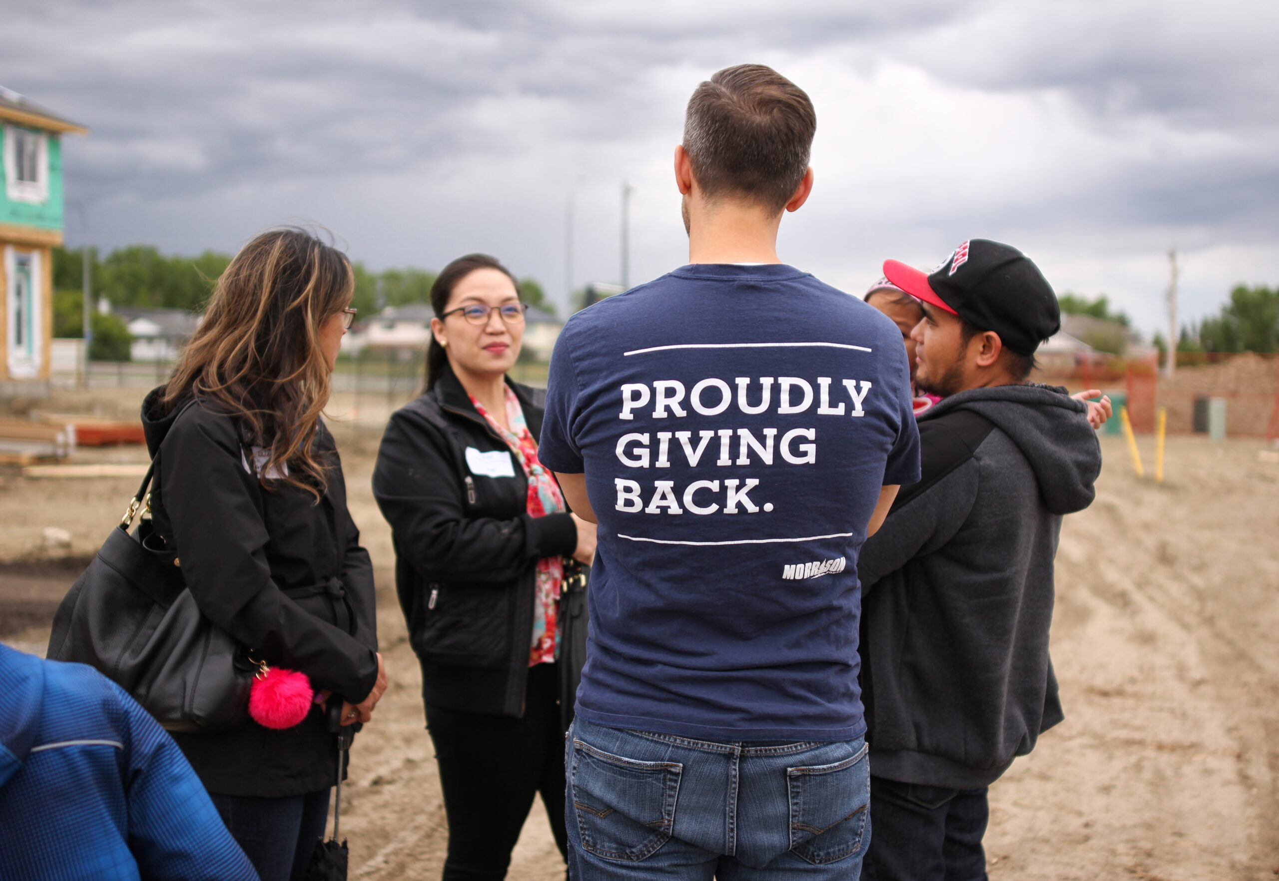 Two future homeowners stand with local committee volunteers from Okotoks at a groundbreaking ceremony. 