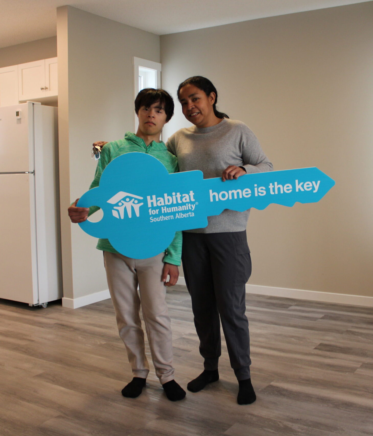 Mildred and her youngest son stand in the living room of their brand new home.