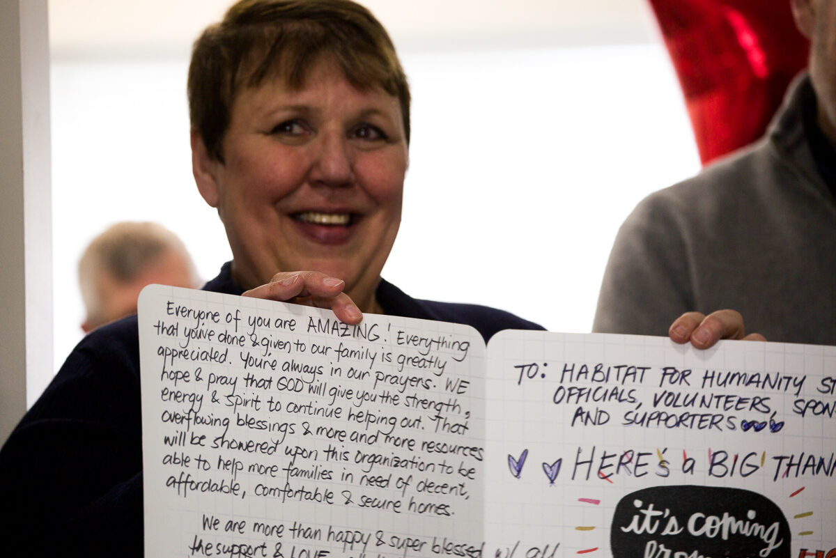 Marilyn shows a large greeting card full of warm wishes that she received from a Habitat homeowner. 