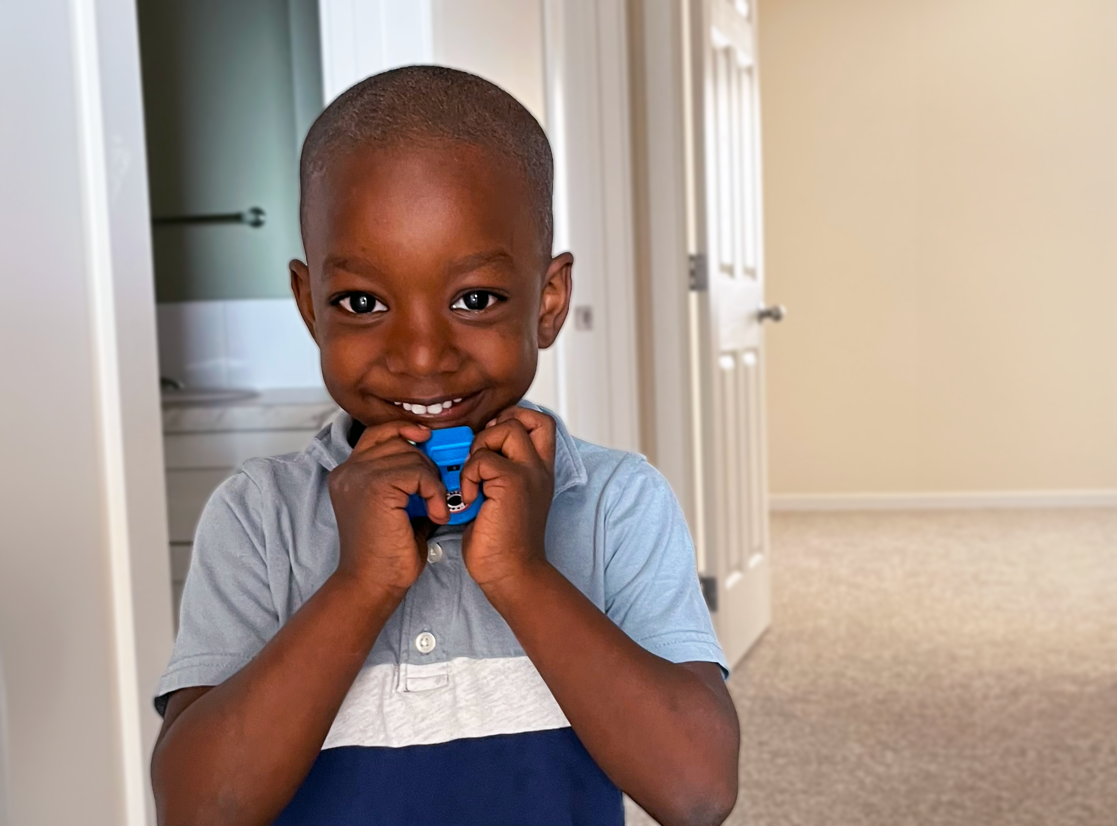 Young boy smiling at camera holding plastic camera
