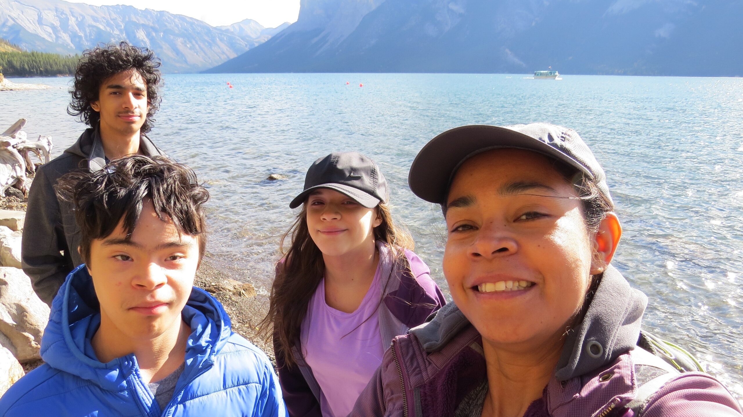 A woman and her three children take a selfie near a mountain lake