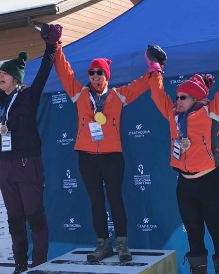 Susan stands on the podium celebrating her two gold medals