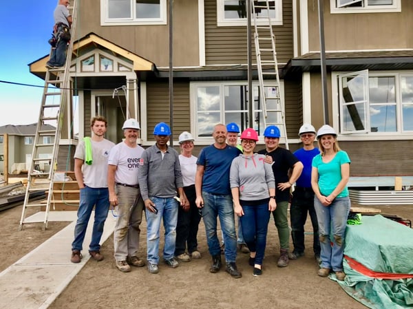 A family and volunteers in front of a Habitat home under construction