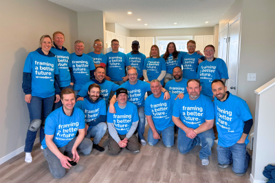 19 team build volunteers gather inside a finished affordable Habitat for Humanity in Southern Alberta.