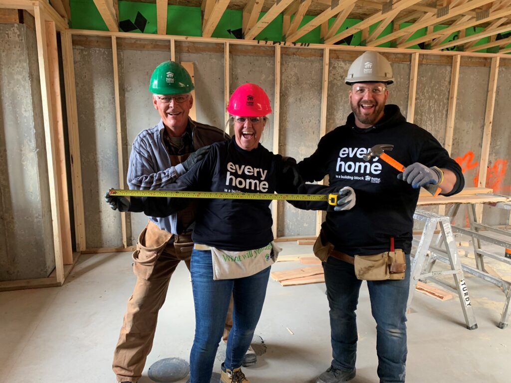 Three volunteers wearing hard hats at the construction site