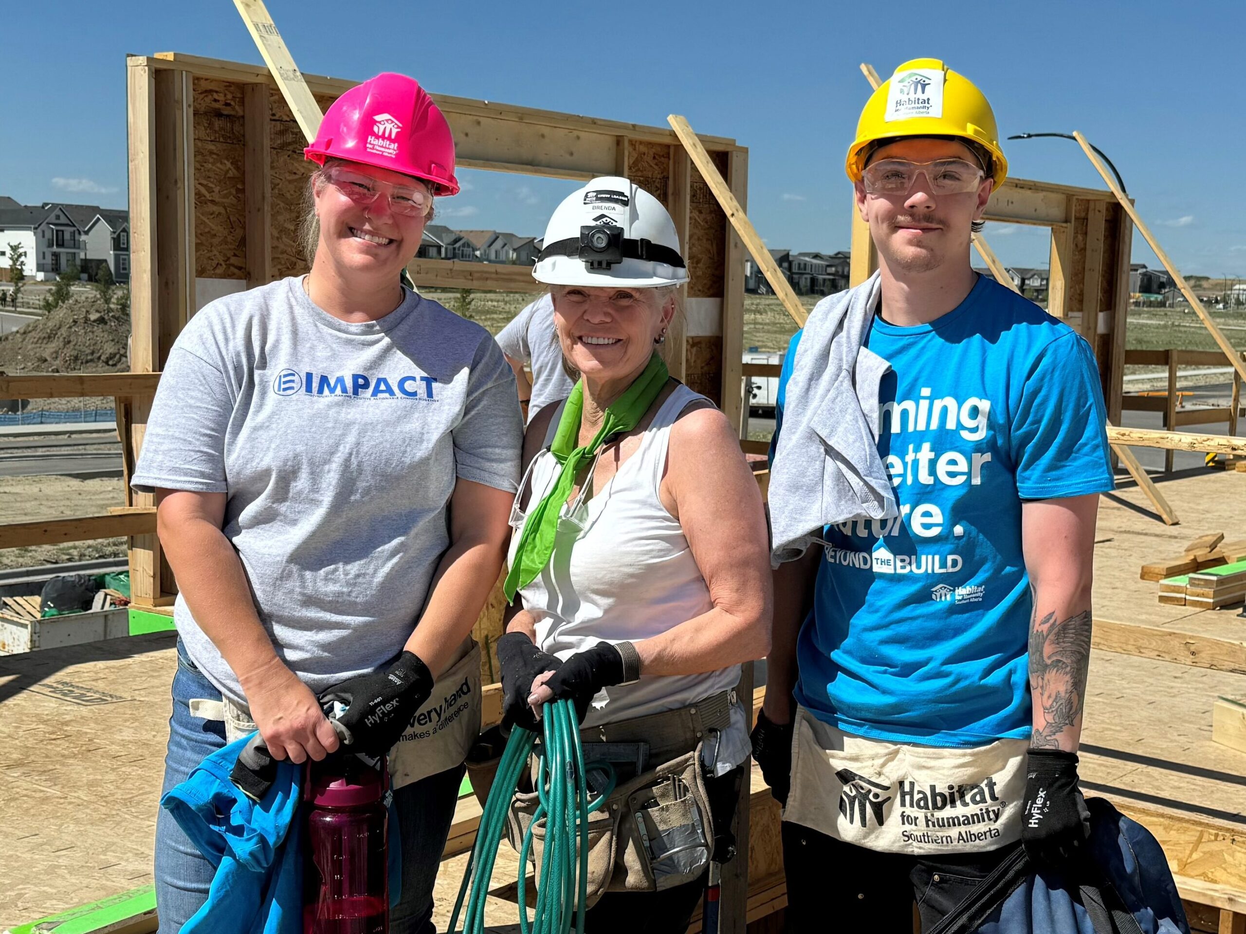 Three Habitat volunteers on an affordable home build site in Calgary.