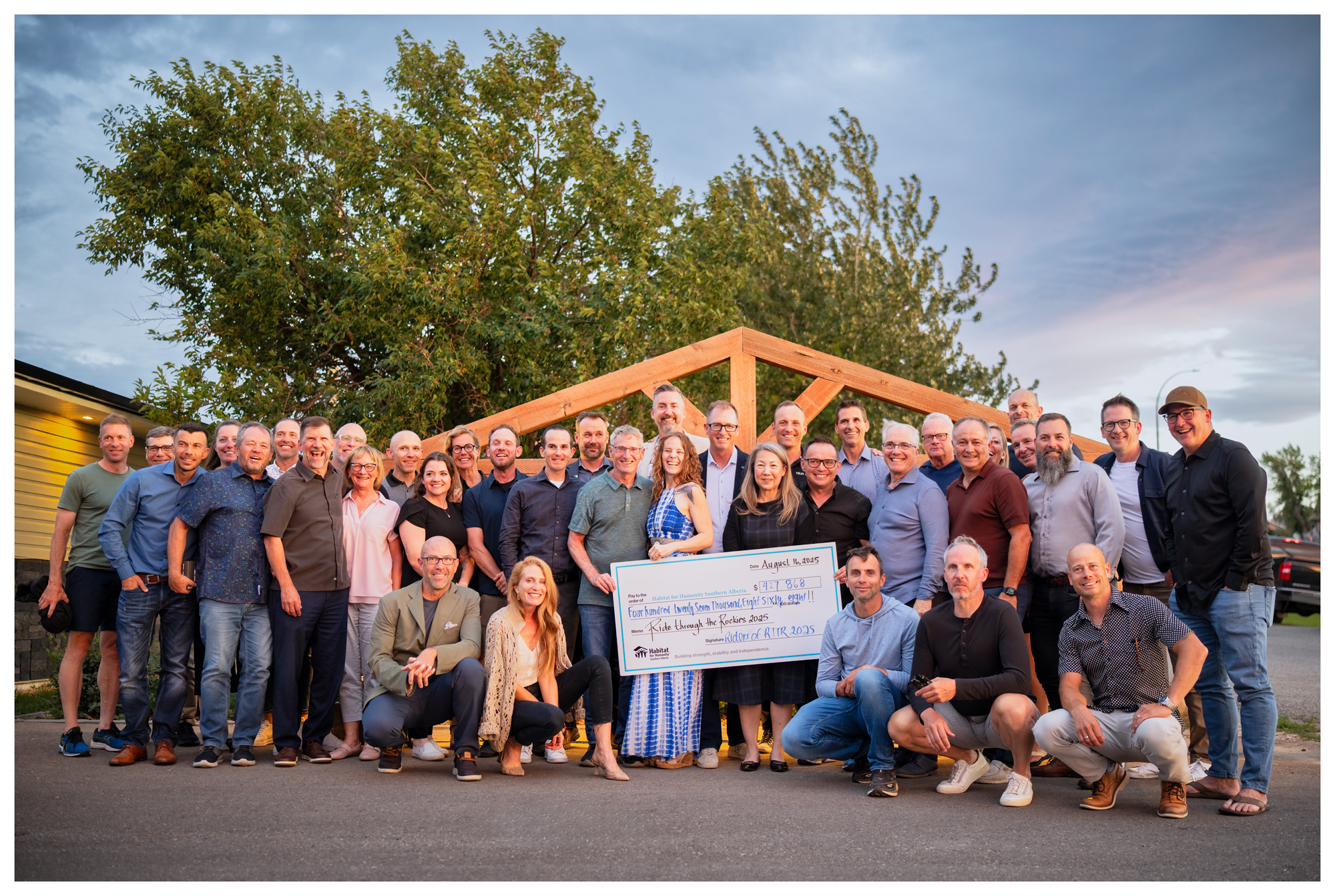 RTTR cyclists stand with a giant cheque showing their fundraising efforts to raise more than $427,000.