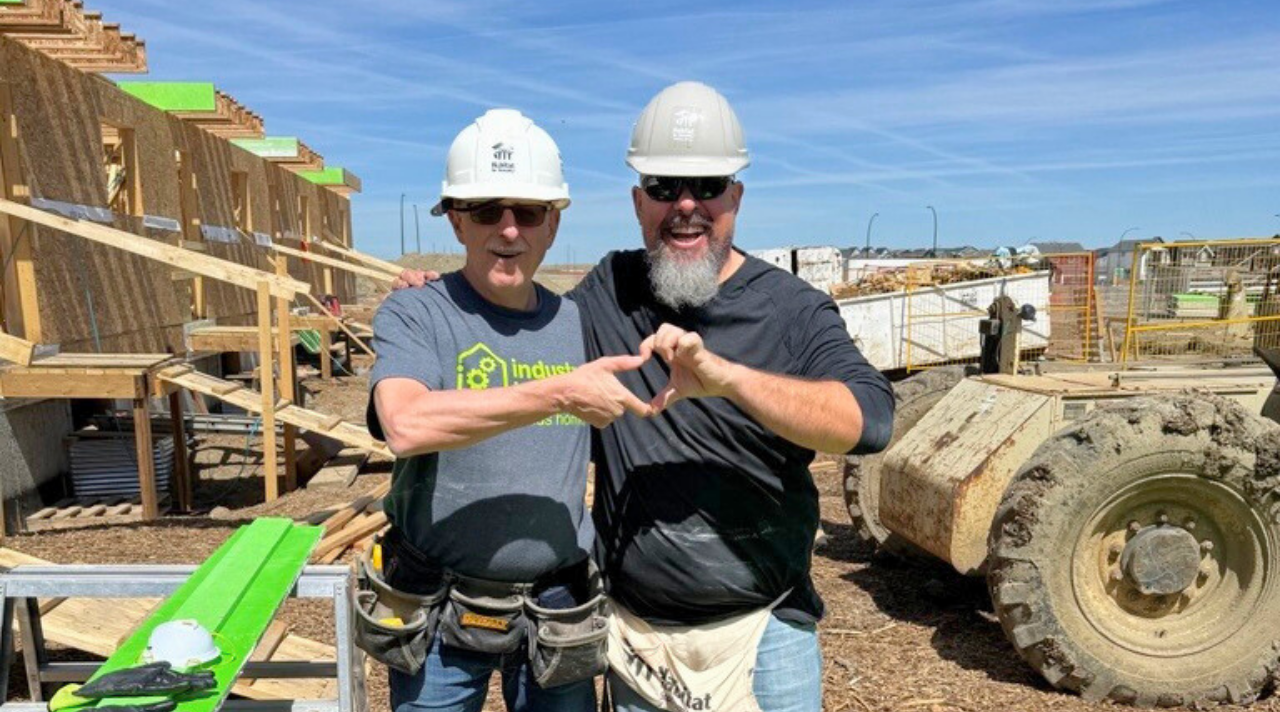 Crew Leader Hugh makes a hand heart with a Build Day participant.