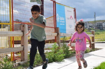 Habitat children running along the sidewalk in front of their future home.