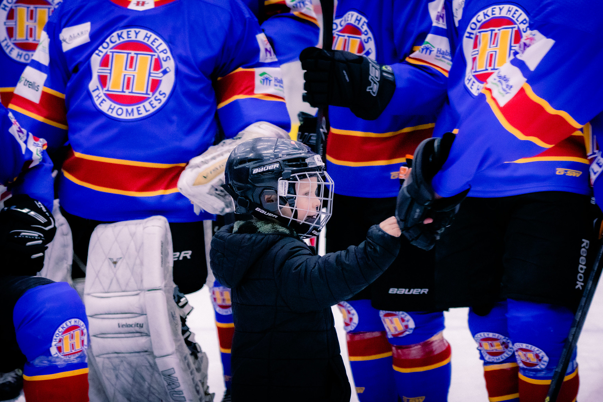 A little boy wearing a hockey helmet fist bumps a HHTH player before the game.