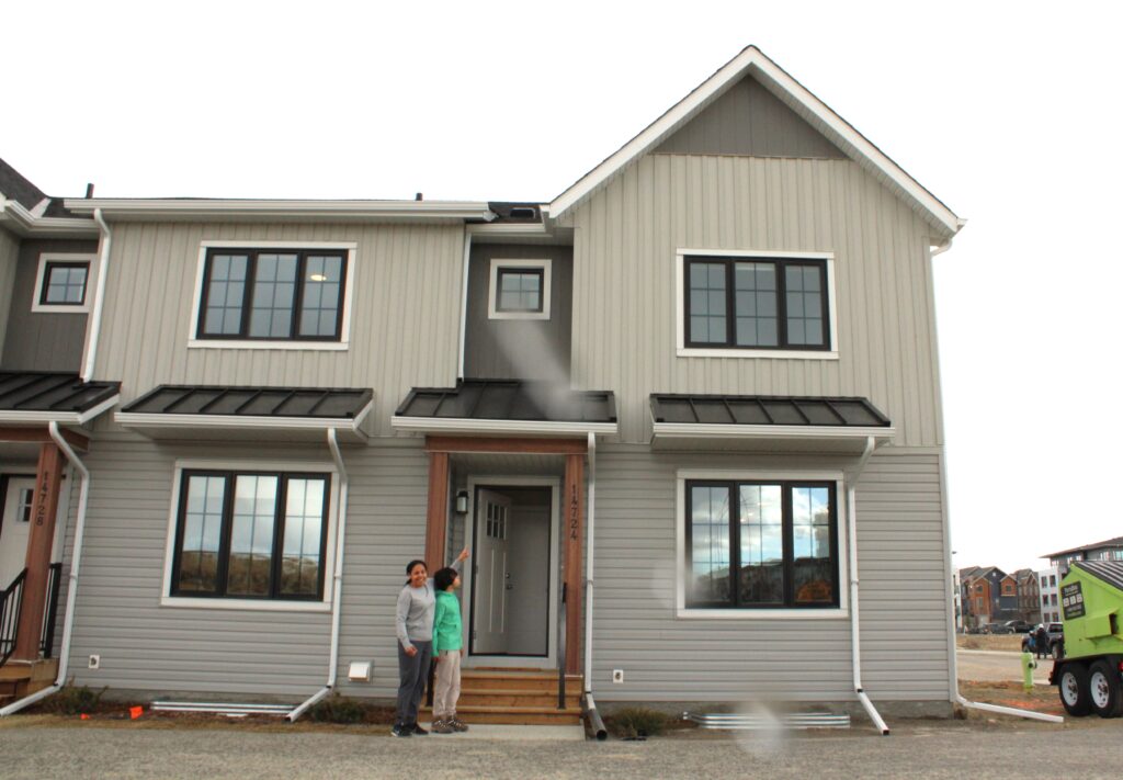 Livingston 24 homeowner Mildred with her son point to their brand new home on possession day.