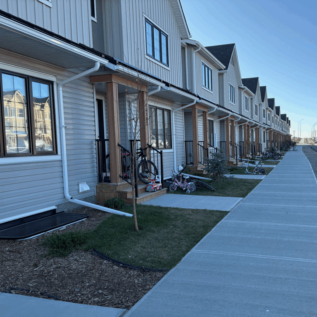 A row of townhouses with kids' bikes out front in the early morning light.