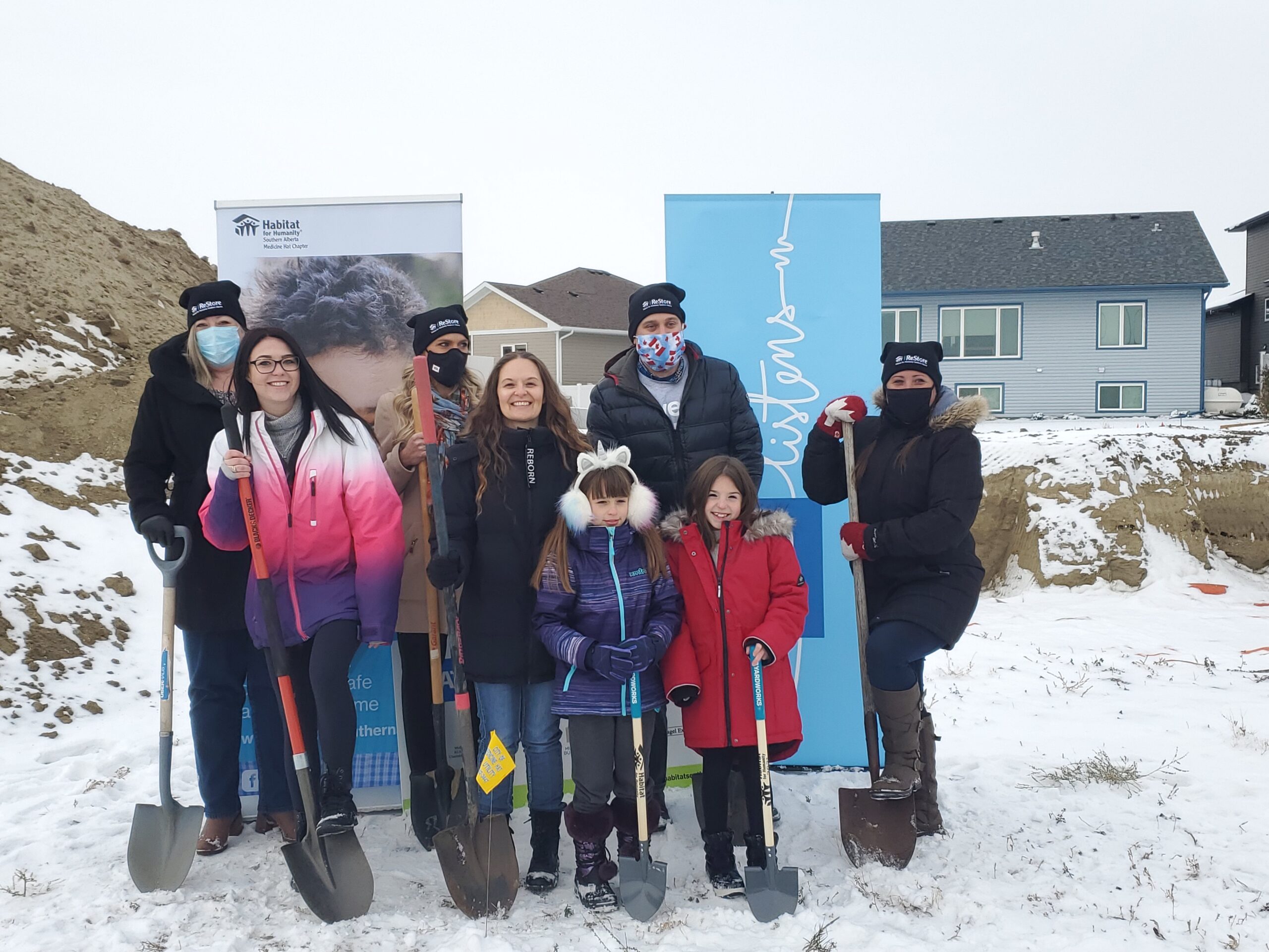 Annette stands on snow covered ground with the future Habitat homeowners in Medicine Hat in 2020.