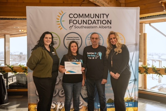 Annette holds a donation of $10,000 with fellow volunteer and two donors from Medicine Hat.