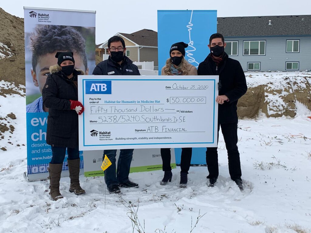 Andrea accepts a cheque for $50,000 from ATB financial, alongside Habitat Southern Alberta's Gerrad Oishi and two employees from ATB financial. 