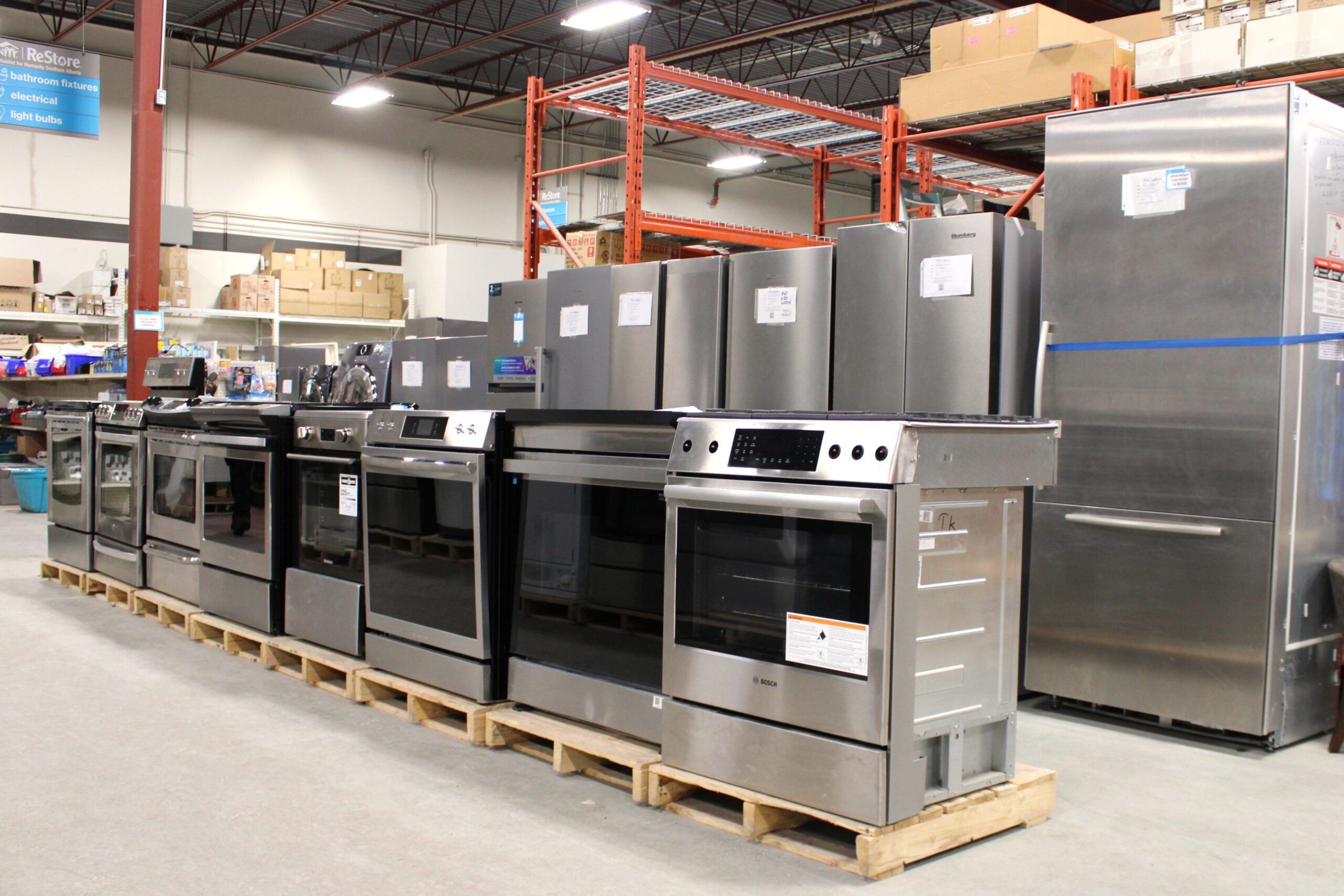 Two rows of scratch and dent fridges and stoves at Habitat ReStore in Calgary.