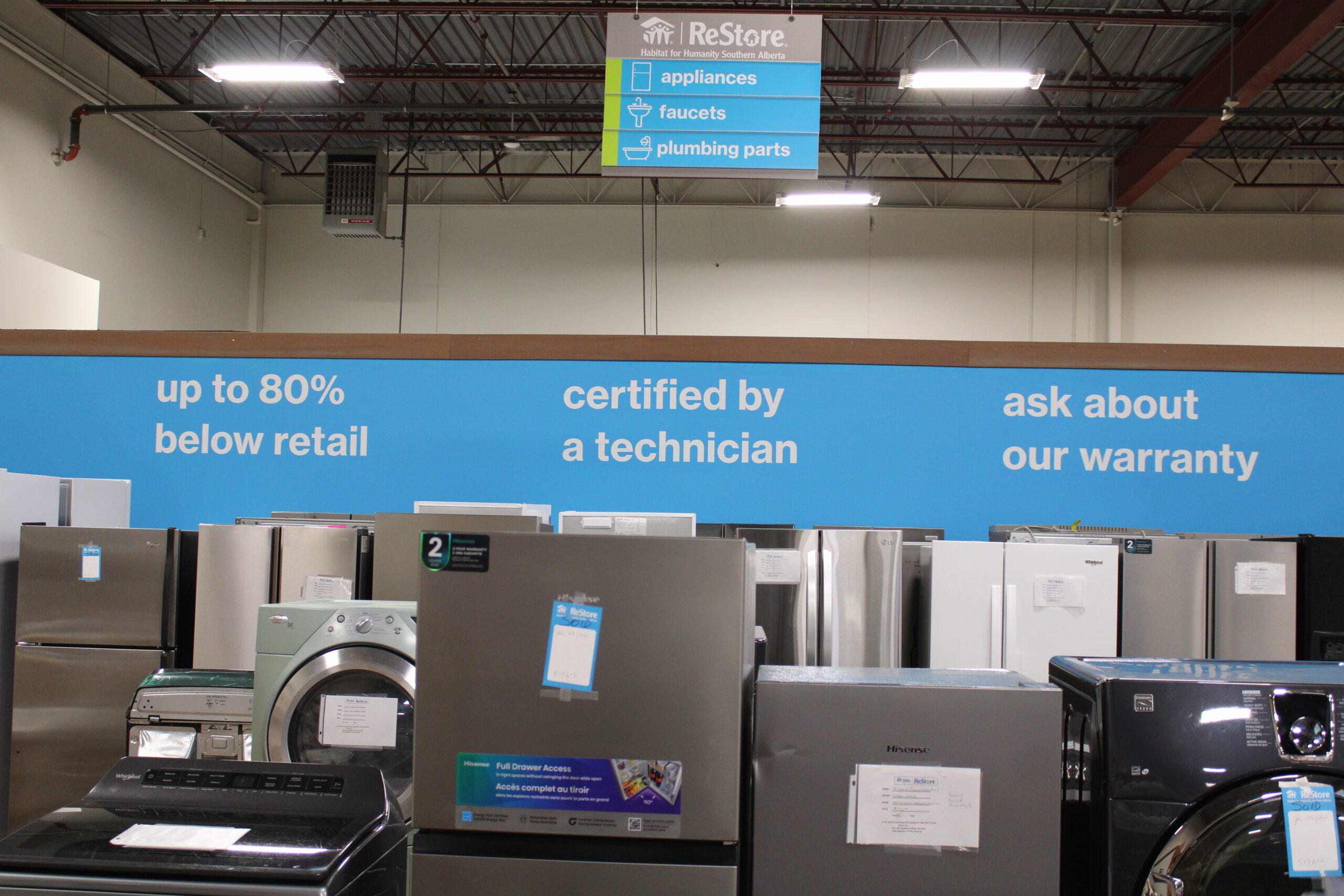 Various major appliances shown against a wall that reads up to 8-% below retail, certified by a technician, ask about our warranty.