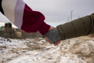 A mom and daughter wearing mitts hold hands