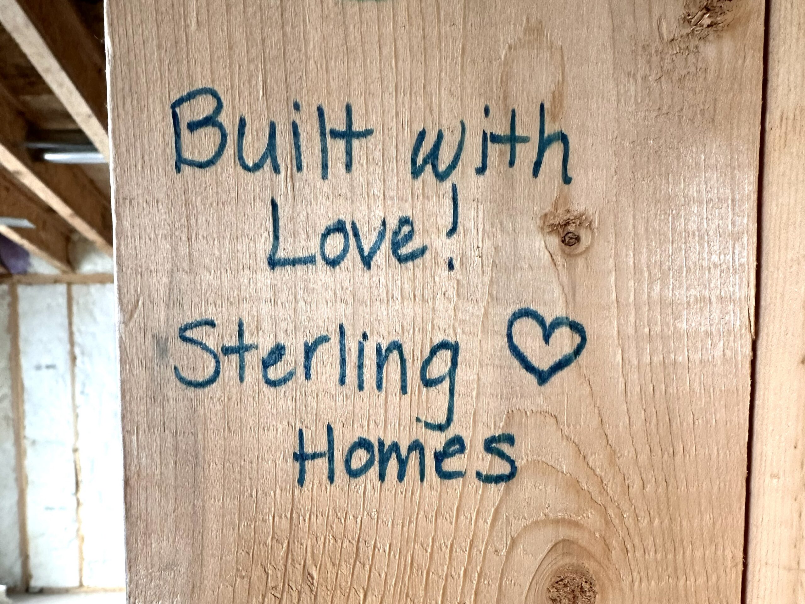 A bare stud with sharpie writing that reads Built with Love! Sterling Homes