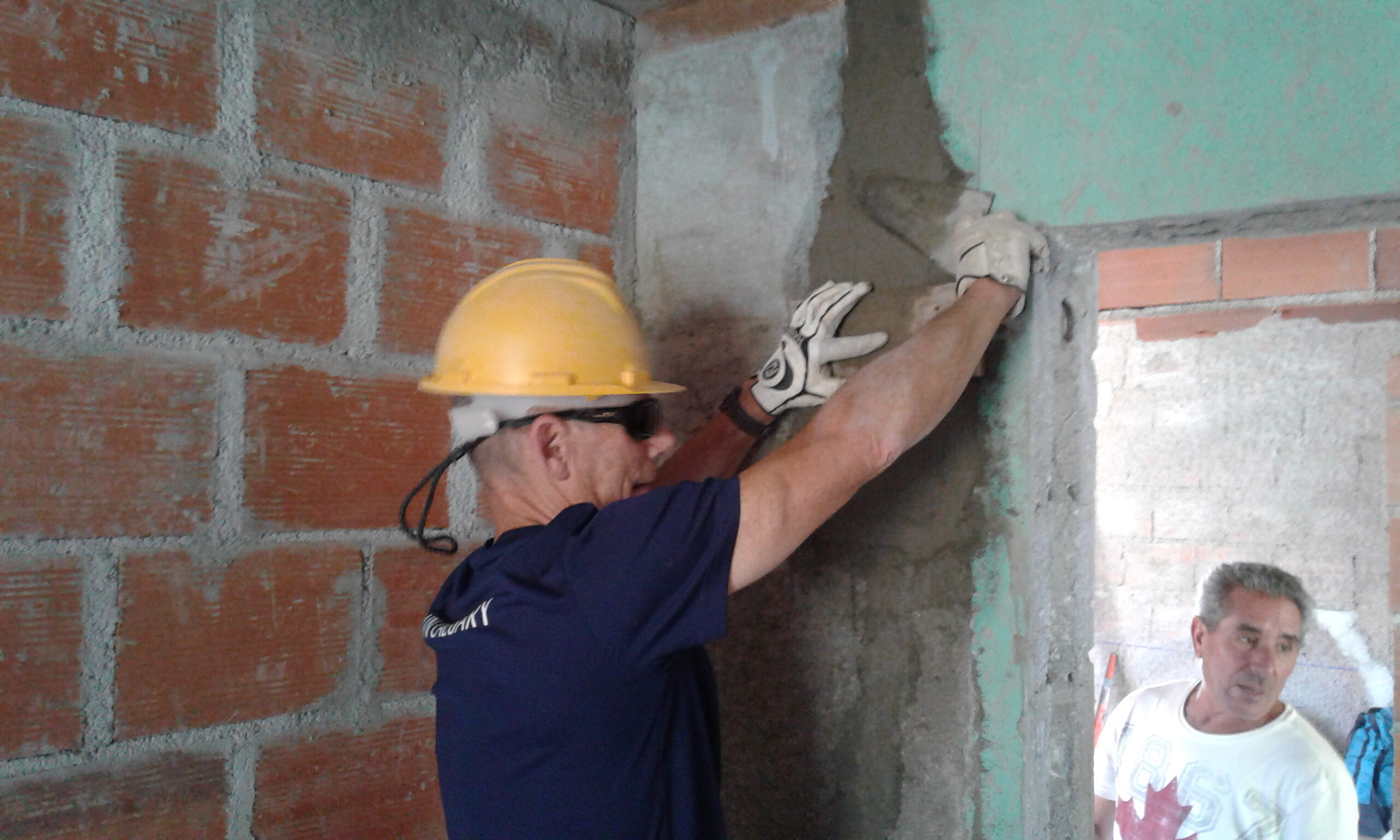A man smears concrete over brick building interior walls in Mexico.